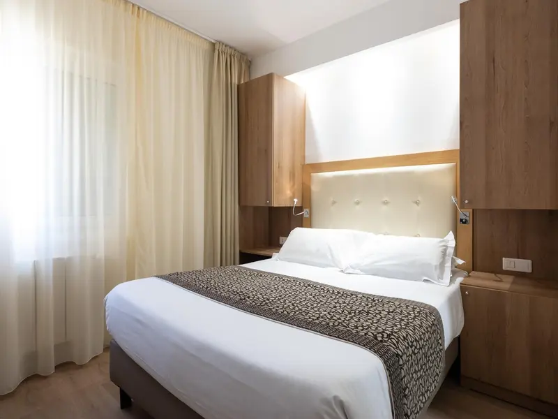 Une chambre lumineuse avec un grand lit recouvert d'une courtepointe.