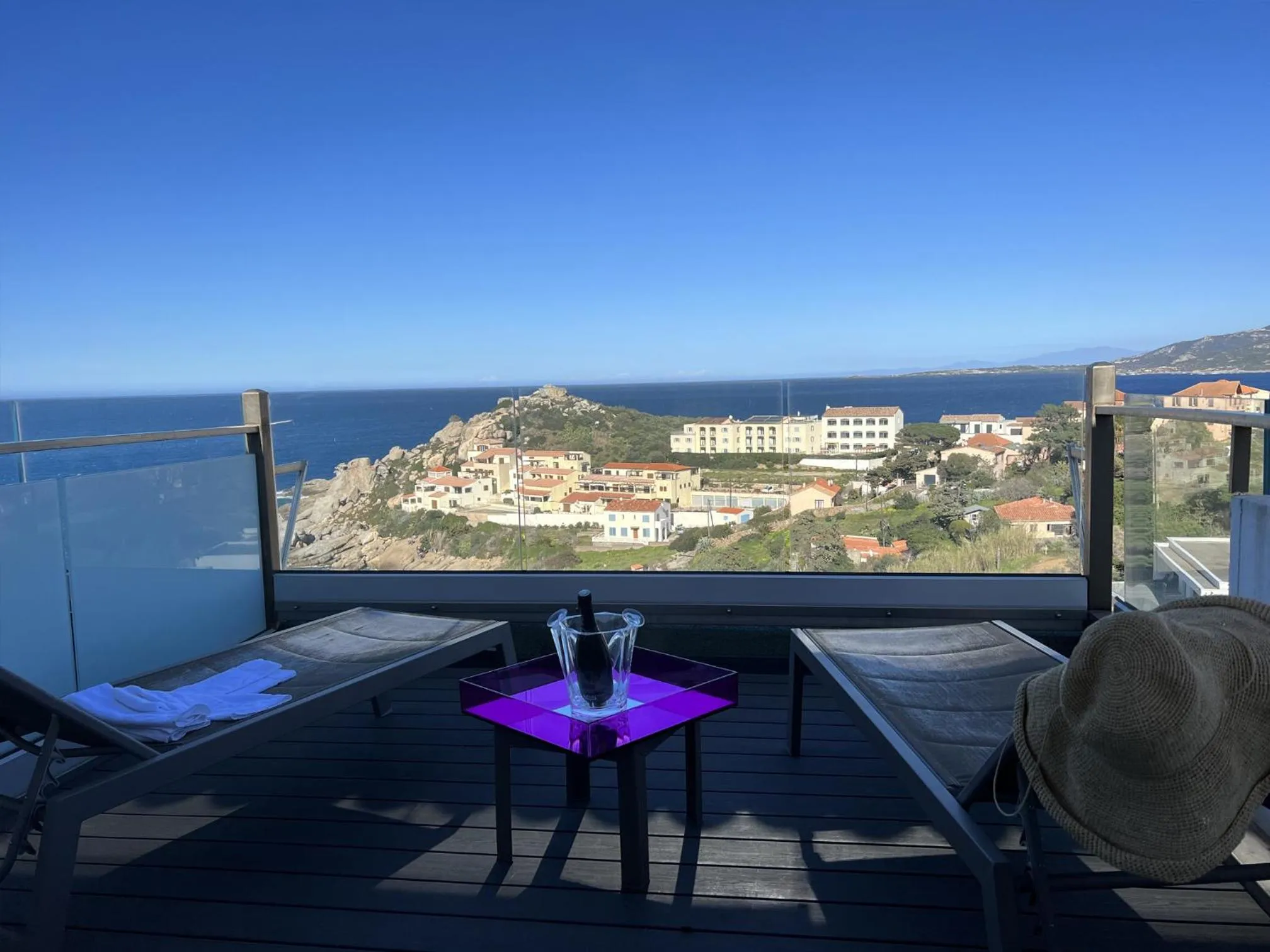 Terrasse avec transats et vue sur la mer et le littoral.