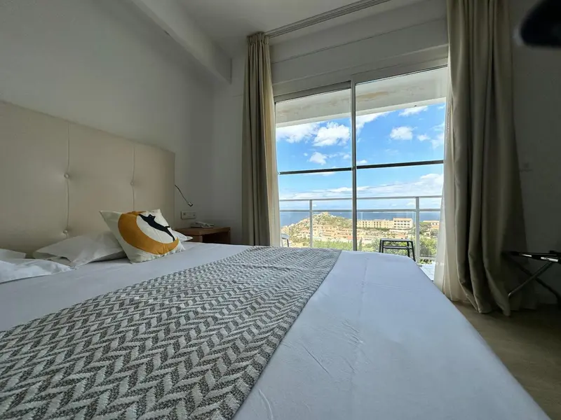 Une chambre lumineuse avec un lit fait donnant sur une vue mer.