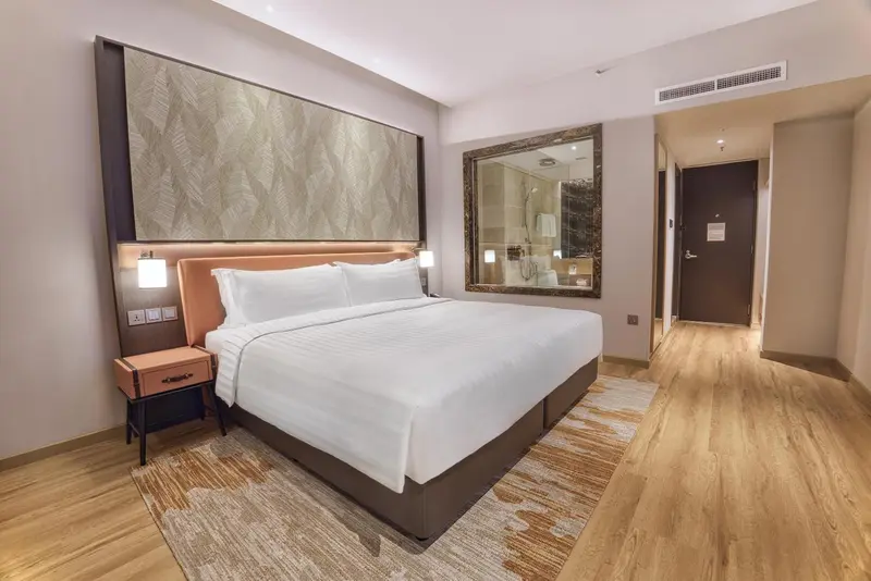 Une chambre d'hôtel moderne avec un grand lit et un décor neutre.