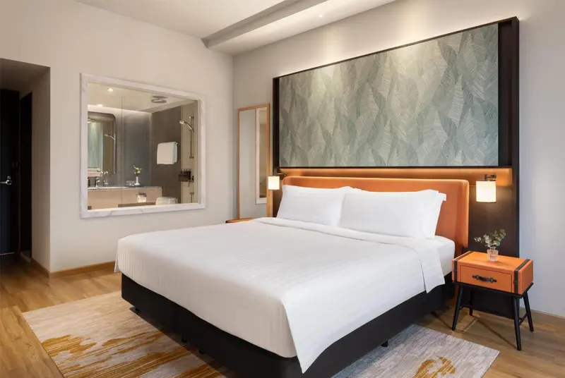 Une chambre d'hotel avec un grand lit et un miroir au-dessus d'un meuble lavabo.