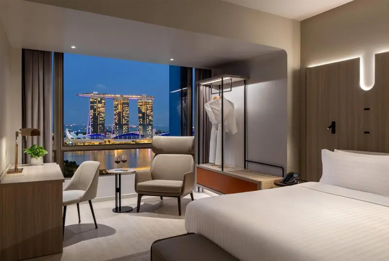 Chambre moderne avec un grand lit et une vue sur la ville illuminée.