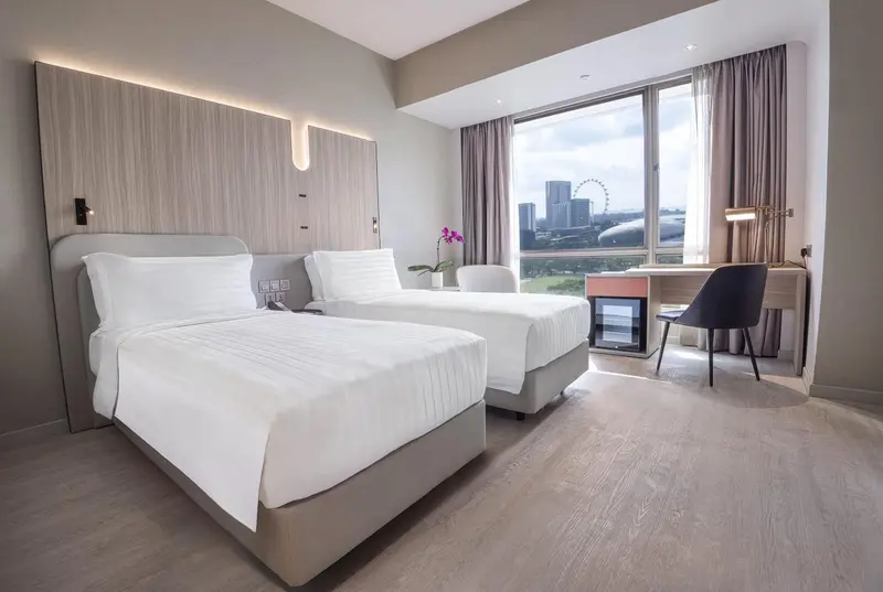 Chambre moderne avec deux lits simples et une grande fenêtre.