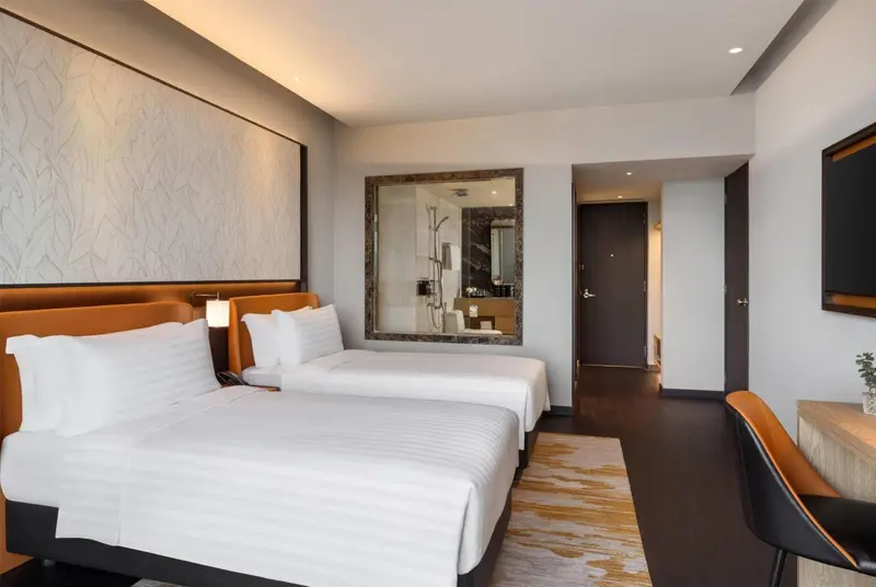 Une chambre moderne avec deux lits simples et un miroir décoratif.
