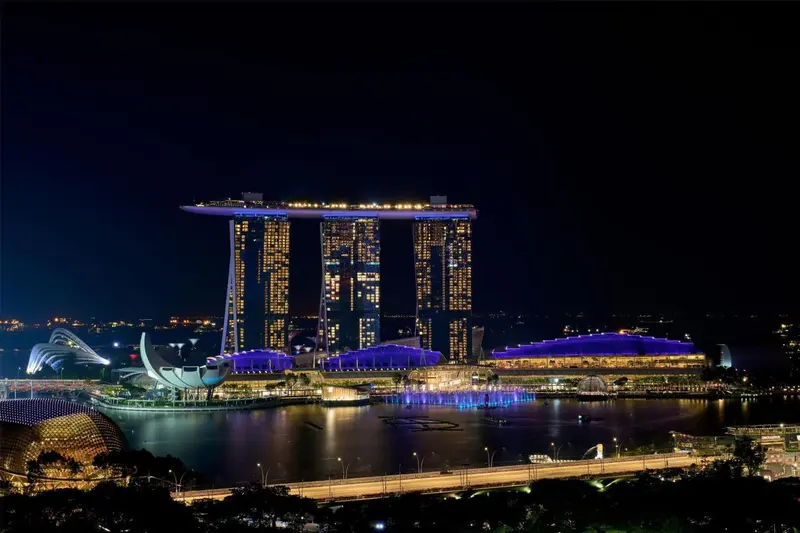 Bâtiment moderne illuminé au bord de l'eau la nuit.