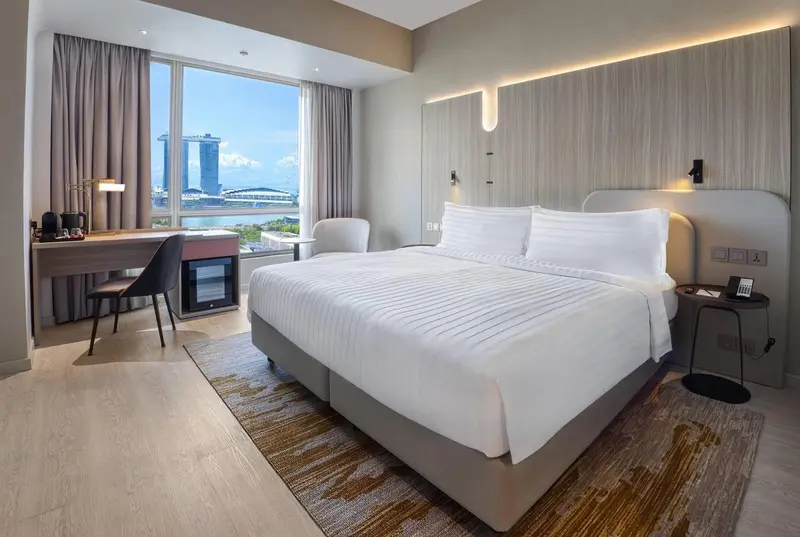 Une chambre lumineuse avec un grand lit et une vue sur la ville.