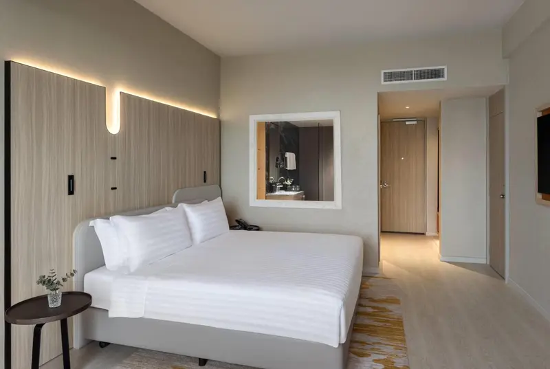Une chambre lumineuse avec un grand lit et un miroir.