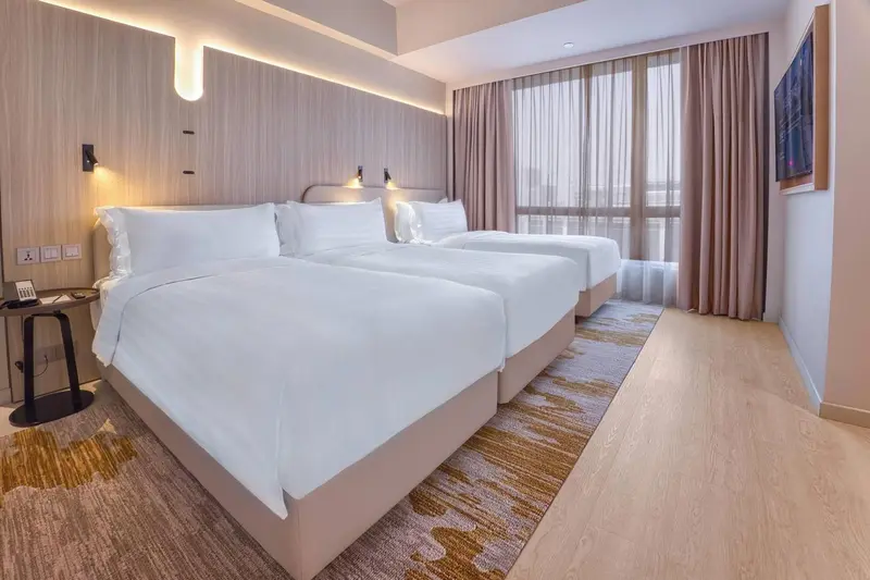 Une chambre lumineuse avec deux lits simples et un tapis décoratif.