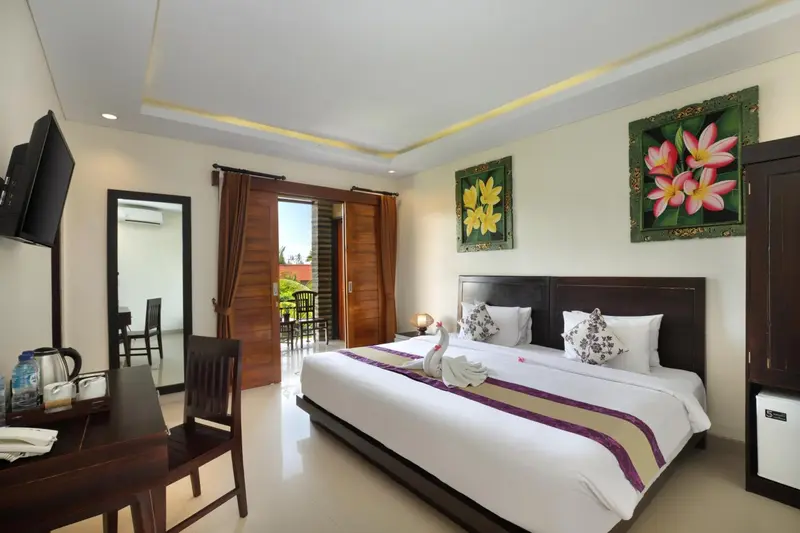 Chambre lumineuse avec un grand lit et une décoration florale.