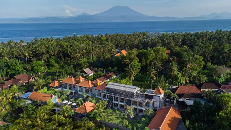 Vue aérienne d'un complexe hôtelier tropical avec une végétation luxuriante et un volcan en arrière-plan.