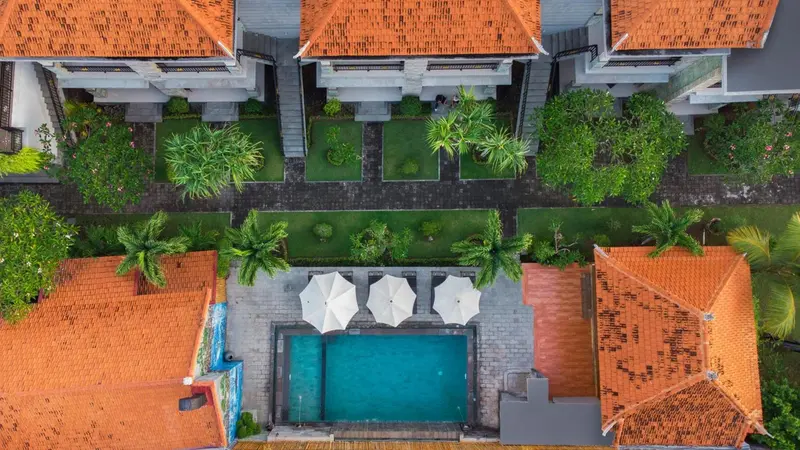 Vue aérienne d'un complexe hôtelier avec piscine et végétation tropicale.