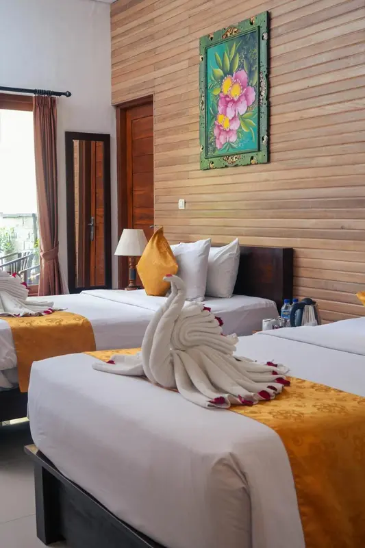 Chambre lumineuse avec deux lits simples décorés de serviettes en forme de cygne.