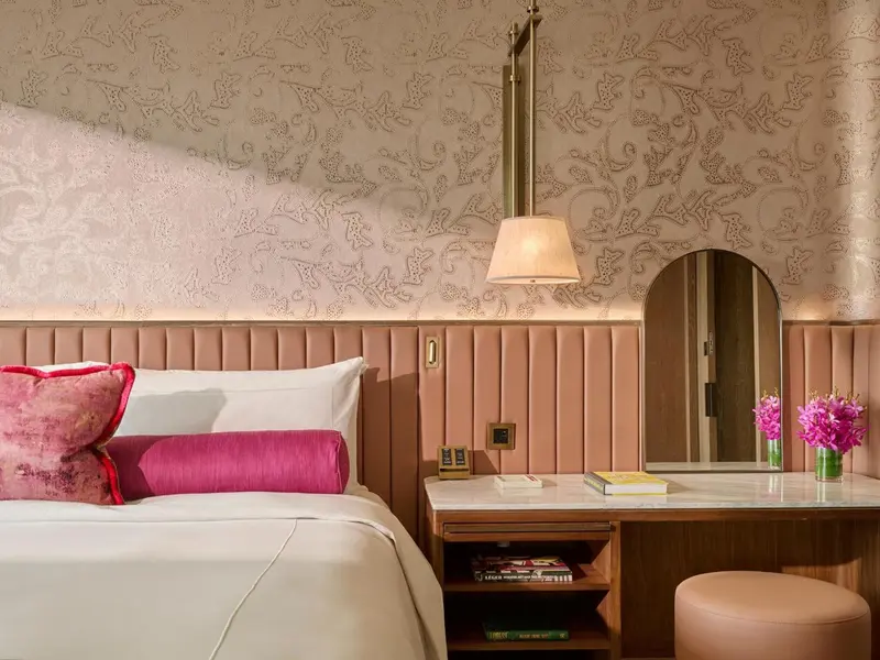 Une chambre à coucher avec un lit recouvert d'une courtepointe blanche et de coussins roses.