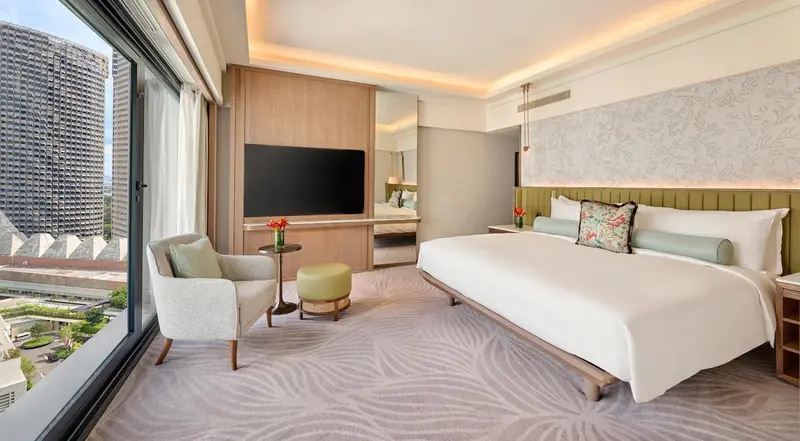 Une chambre lumineuse avec un grand lit et un coin salon près d'une fenêtre.