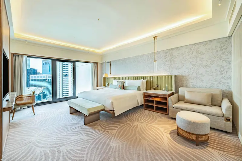 Chambre lumineuse avec un grand lit et un coin salon.