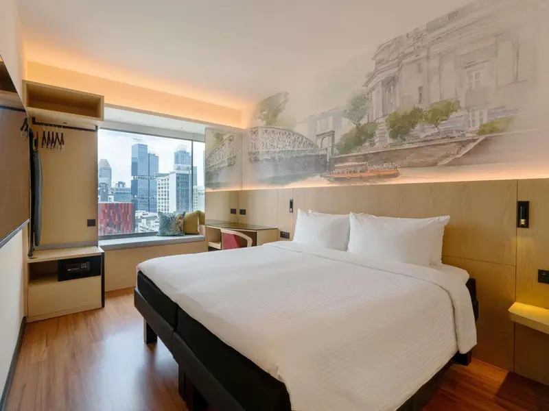 Une chambre lumineuse avec un grand lit et une vue sur la ville.