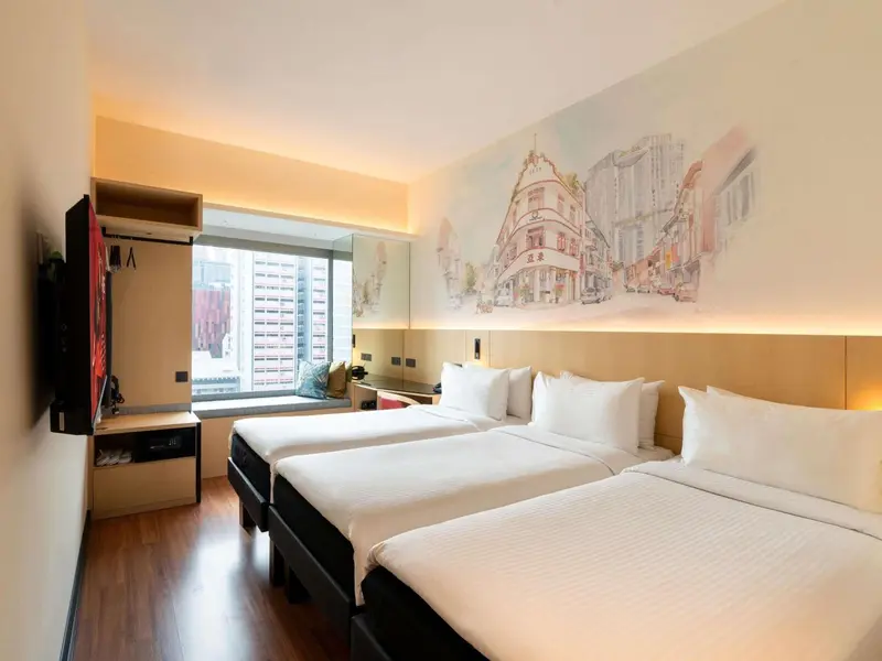 Chambre d'hôtel lumineuse avec deux lits simples et une décoration murale.