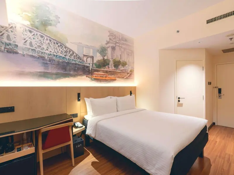 Une chambre d'hôtel lumineuse avec un grand lit et une décoration murale représentant un pont.