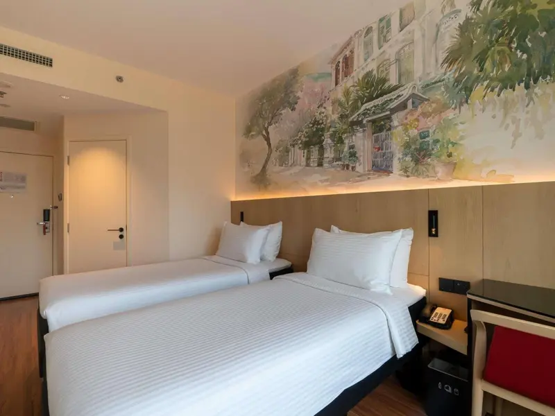 Une chambre lumineuse avec deux lits simples et une décoration murale représentant une scène de rue.