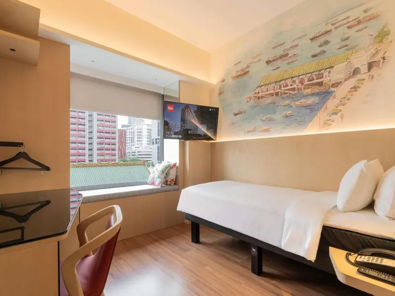 Une chambre d'hôtel lumineuse avec un lit simple et une décoration murale représentant des bateaux.