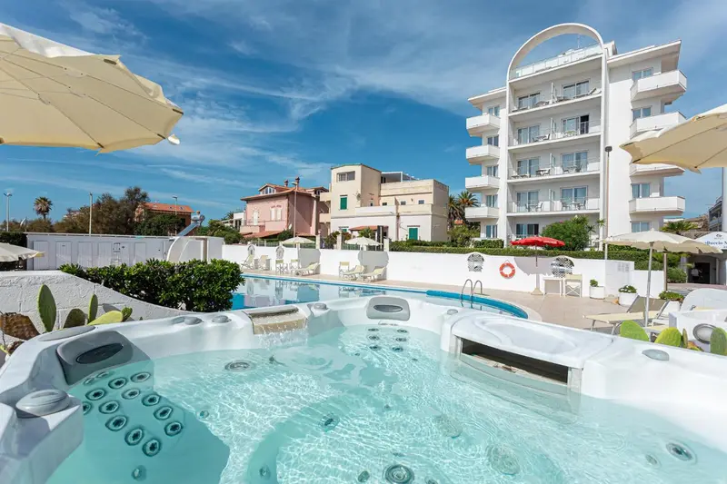 Piscine et jacuzzi avec bâtiments blancs en arrière-plan sous un ciel bleu.
