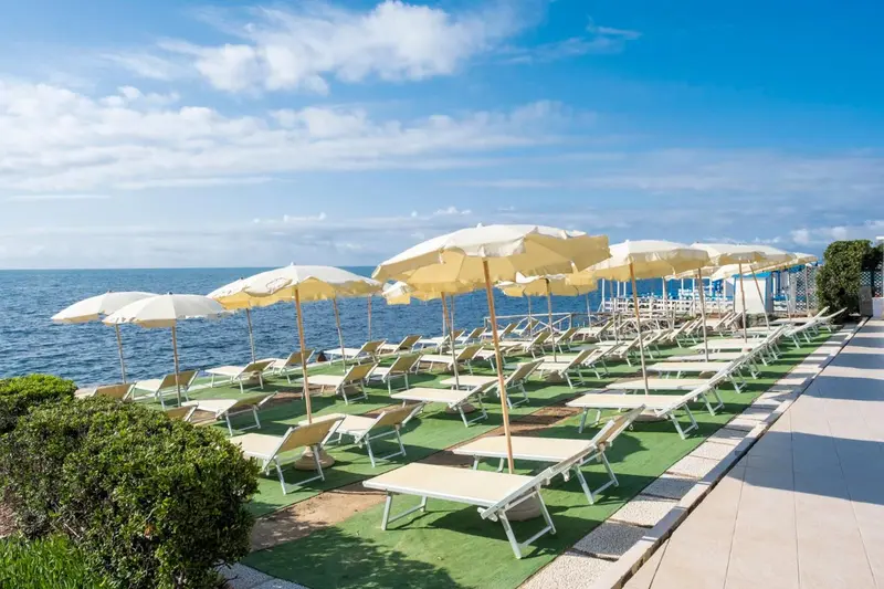Transats et parasols alignés sur une terrasse en bord de mer.