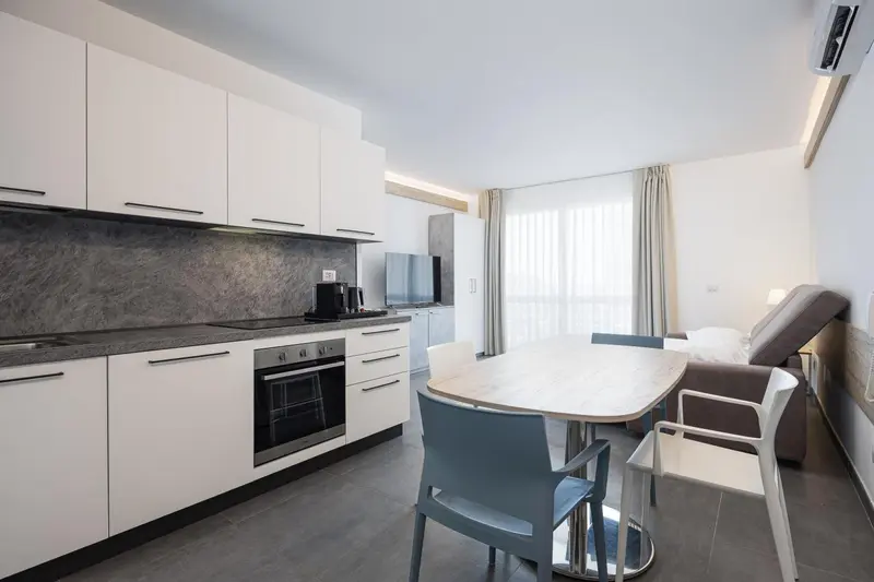 Une cuisine moderne s'ouvre sur un espace repas lumineux avec vue sur l'extérieur.