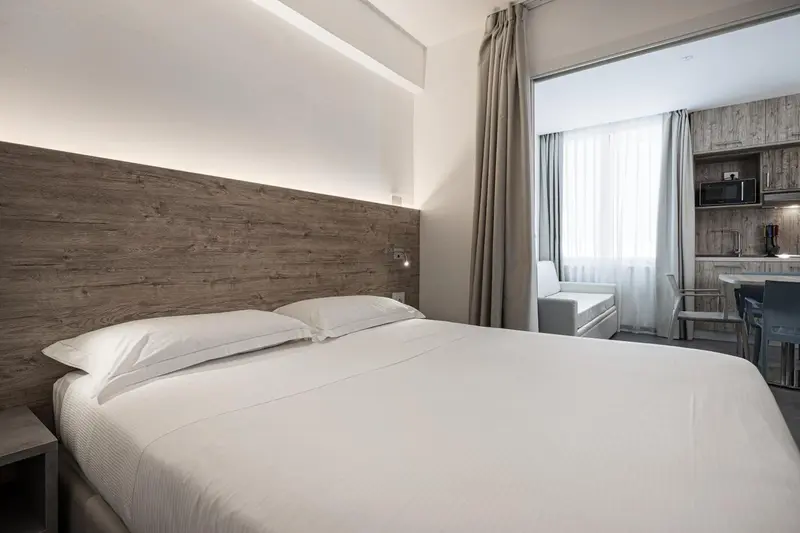 Une chambre lumineuse avec un grand lit et un coin cuisine.