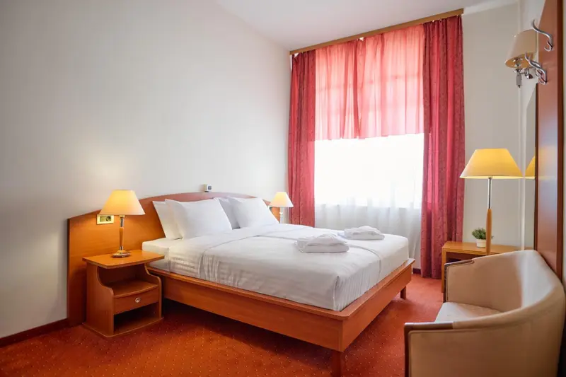 Une chambre d'hôtel lumineuse avec un grand lit et des rideaux rouges.