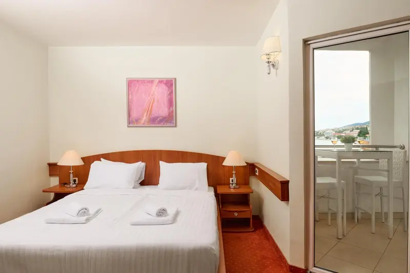 Une chambre lumineuse avec un lit double et un accès à un balcon.