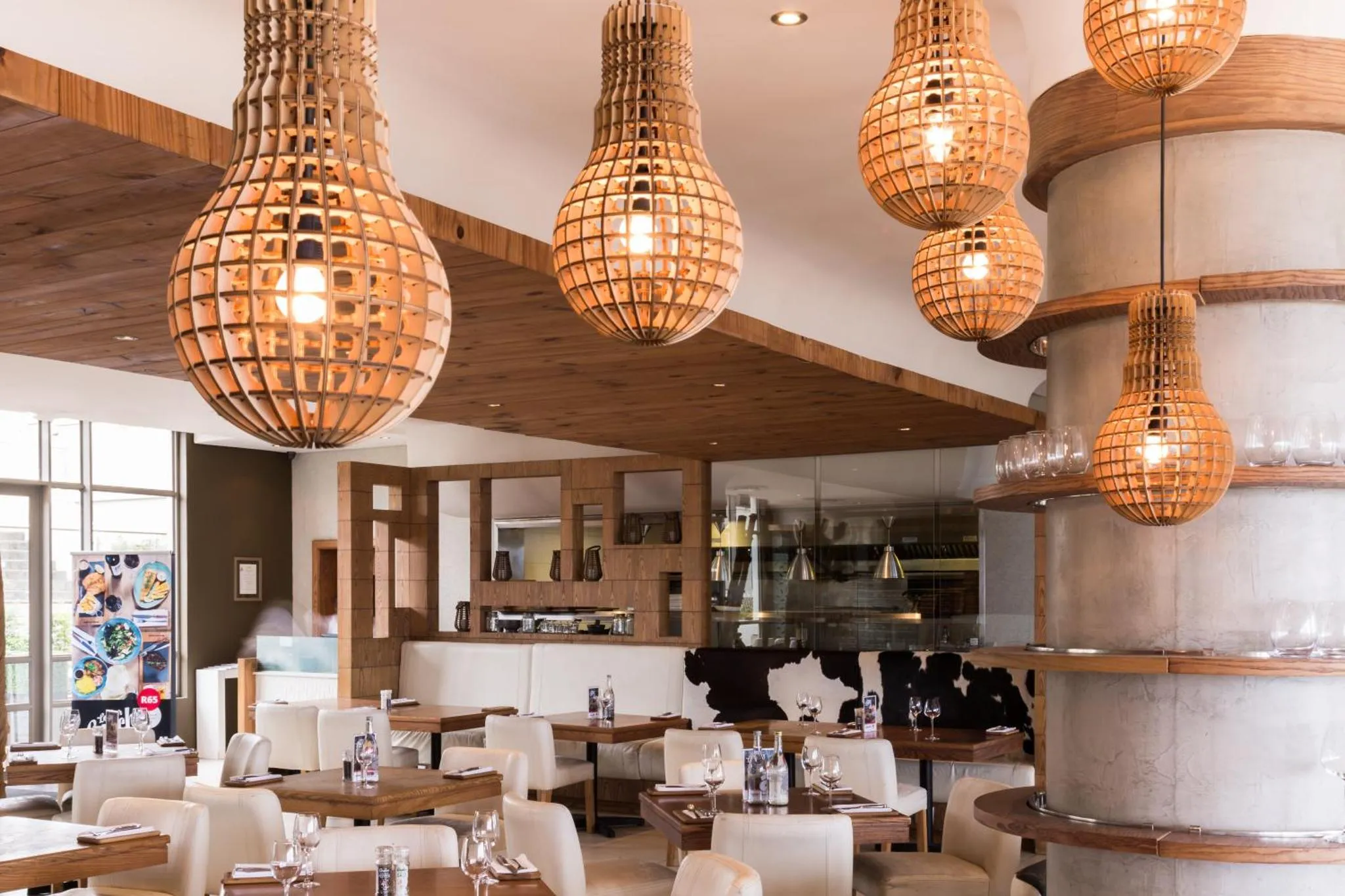 Une salle lumineuse avec des luminaires en osier et des tables dressées pour un repas.