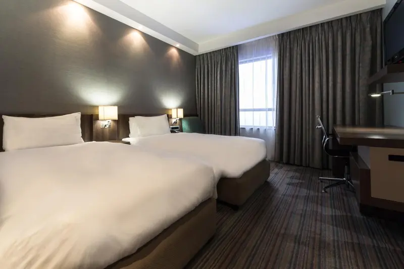 Une chambre d'hôtel moderne avec deux lits simples et un bureau.