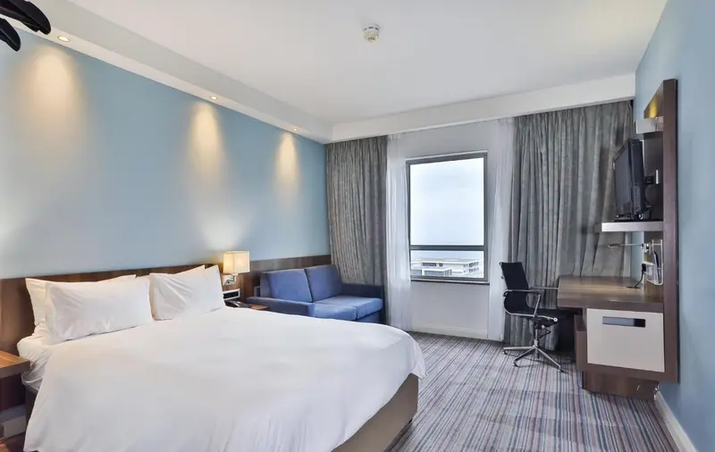 Une chambre d'hôtel lumineuse avec un lit double et un espace bureau.