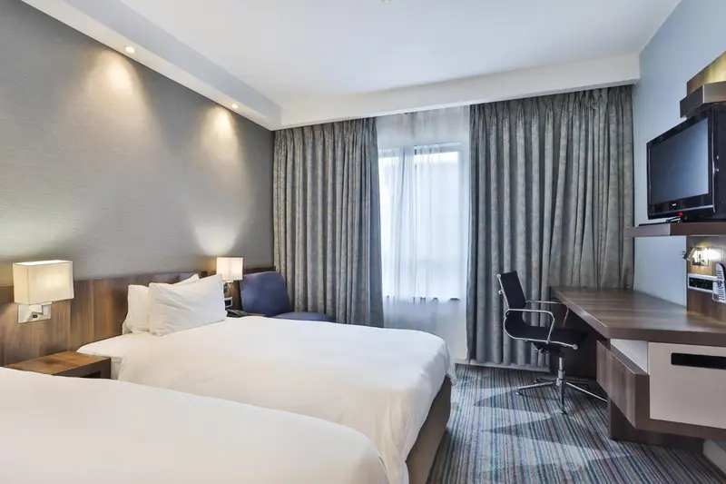 Une chambre d'hôtel lumineuse avec deux lits simples et un espace de travail.