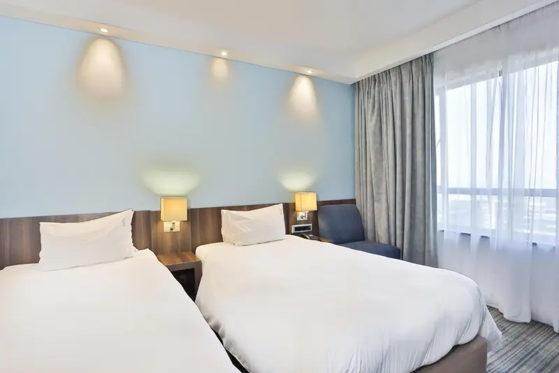 Une chambre d'hôtel avec deux lits simples et un fauteuil.