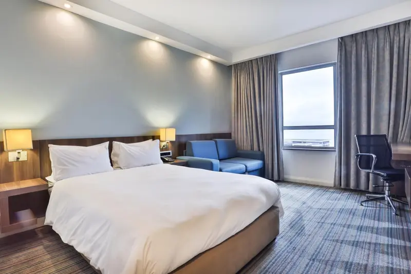 Chambre d'hôtel lumineuse avec un lit double et un coin salon.