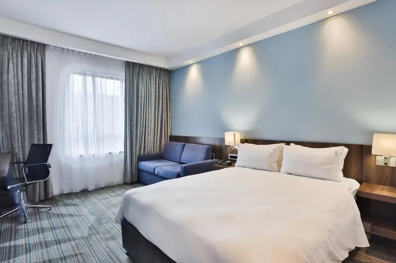 Une chambre d'hôtel lumineuse avec un lit et un coin salon.