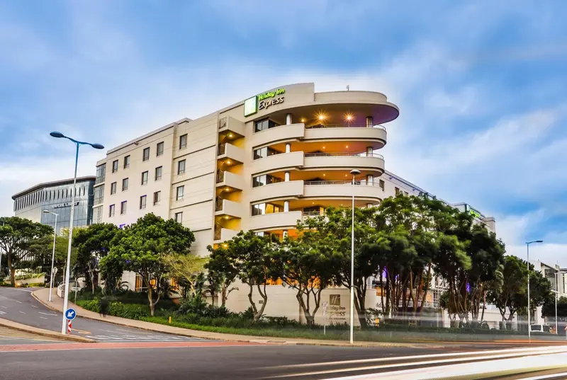 Bâtiment moderne avec des balcons et une végétation luxuriante en bord de route.