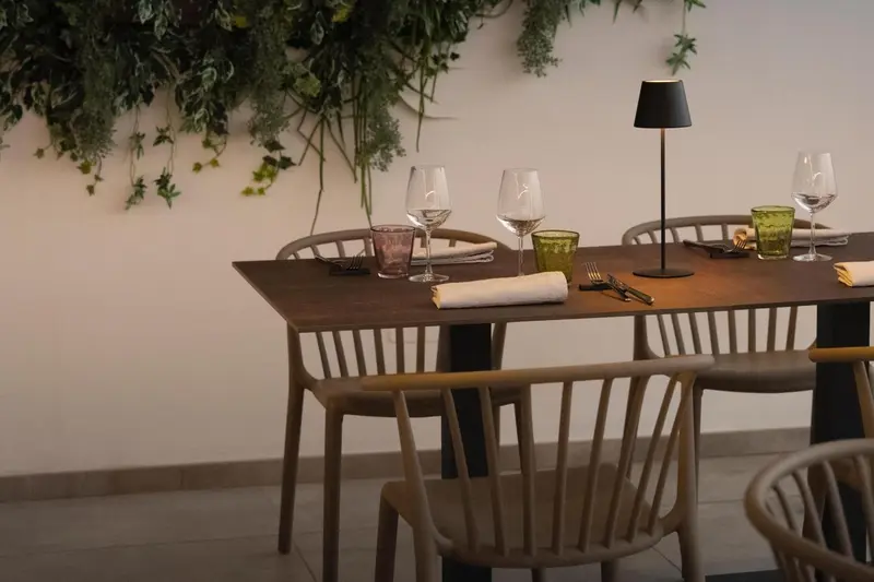 Une table est dressée dans une salle à manger avec des chaises en bois et des verres.