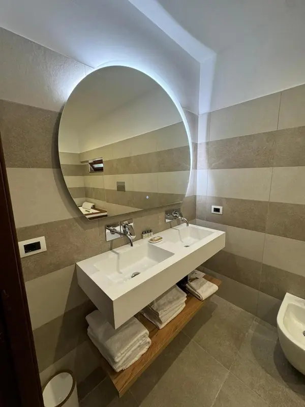 Une salle de bain moderne avec un double vasque et un grand miroir rond.