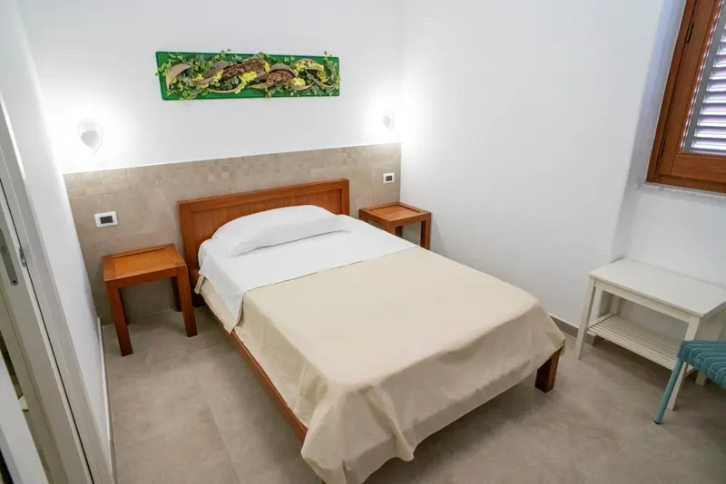 Une chambre lumineuse avec un lit simple et des tables de chevet en bois.