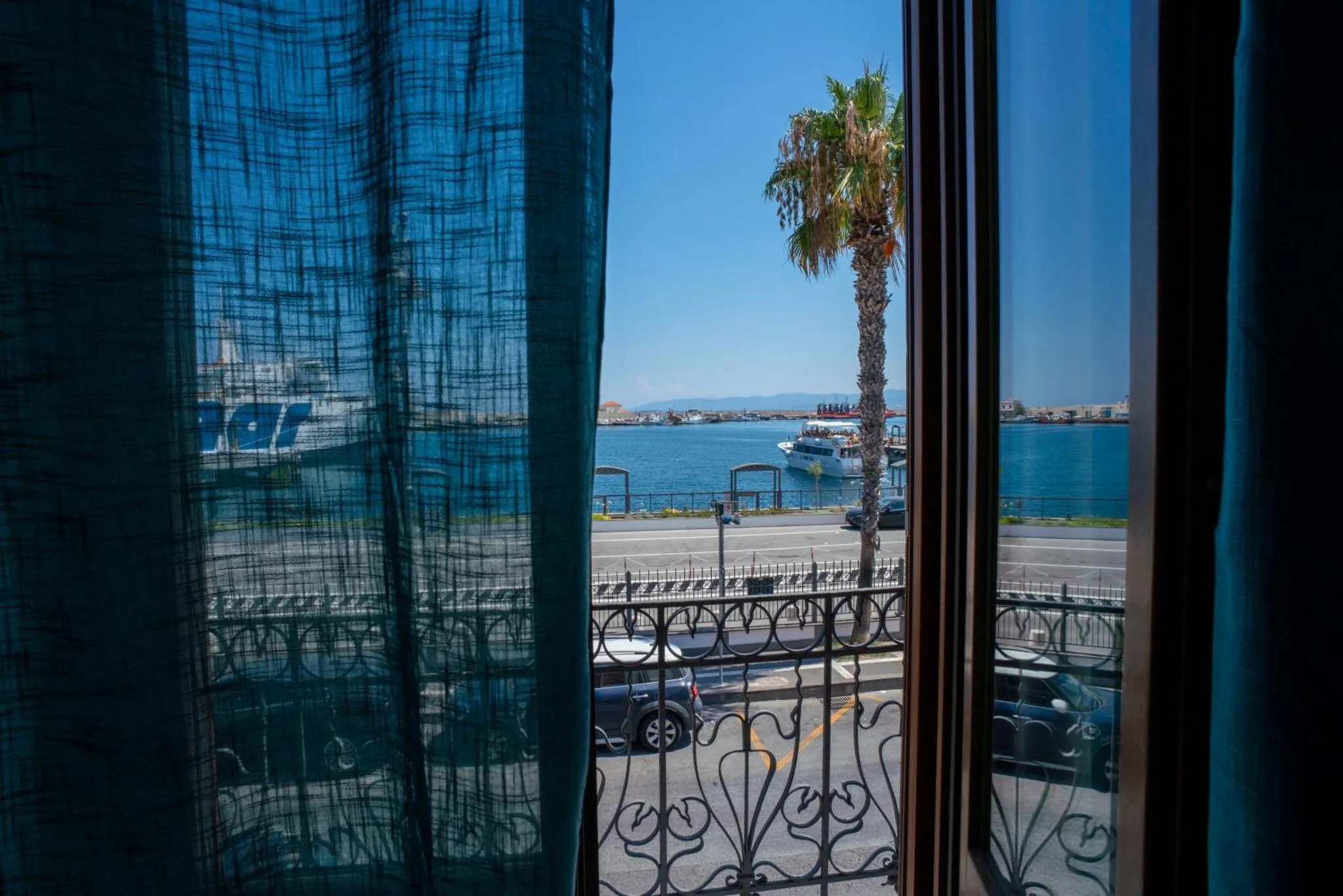 Vue sur la mer depuis une fenêtre avec des rideaux bleus.
