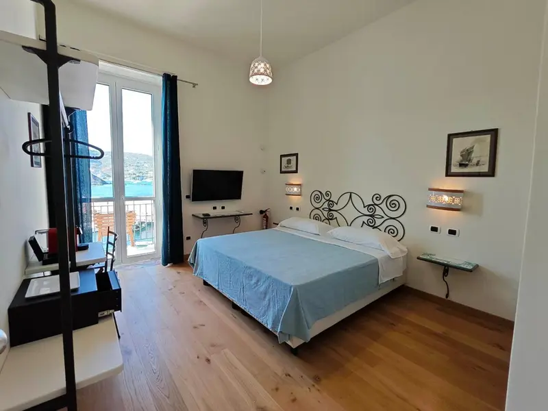 Une chambre lumineuse avec un grand lit et un bureau près d'une fenêtre.