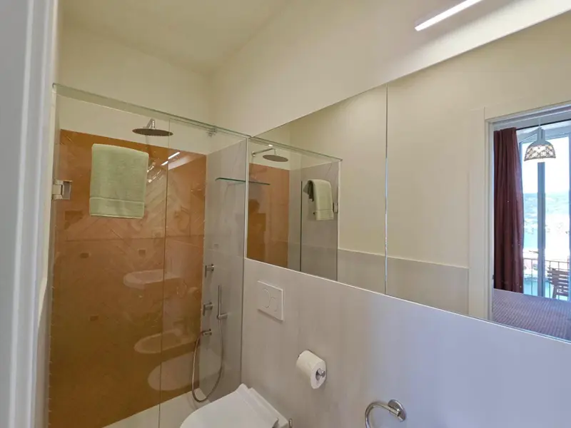 Douche à l'italienne dans une salle de bain moderne avec carrelage orange et miroir.