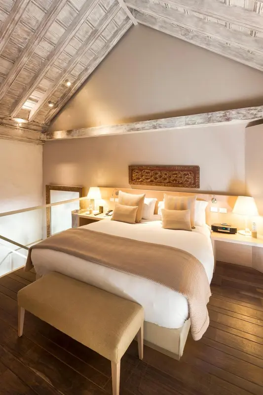 Une chambre lumineuse avec un grand lit recouvert d'une couverture et de coussins.