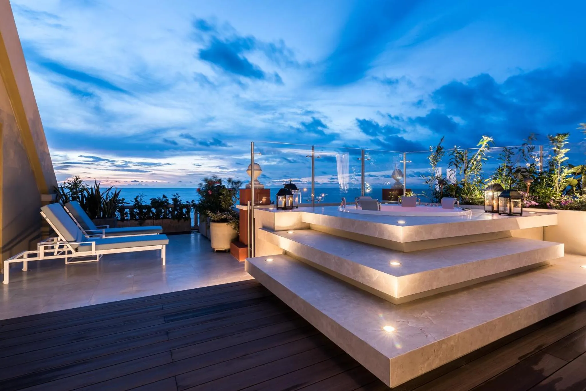 Terrasse lumineuse avec mobilier de détente et vue sur la mer au crépuscule.