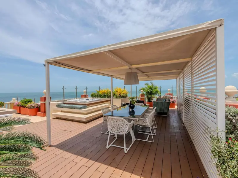 Une table à manger est placée sur une terrasse en bois avec un jacuzzi.