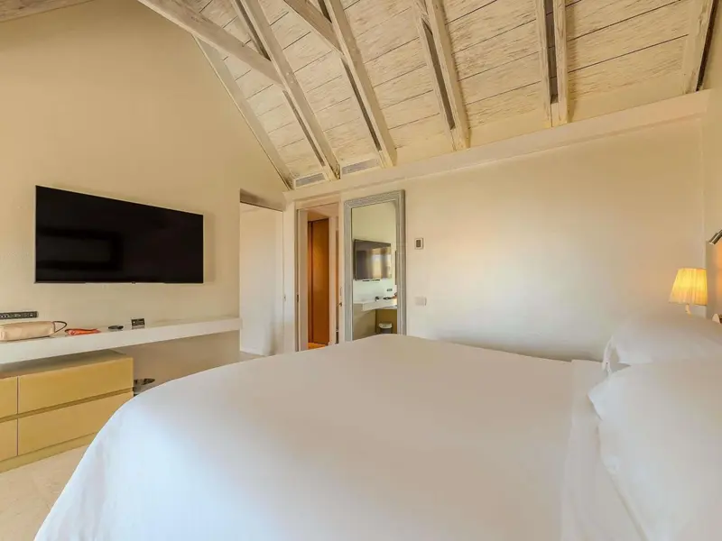 Une chambre lumineuse avec un grand lit et une télévision murale.