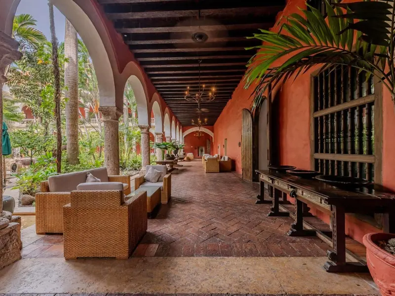 Galerie ouverte sur un jardin tropical avec des salons confortables.