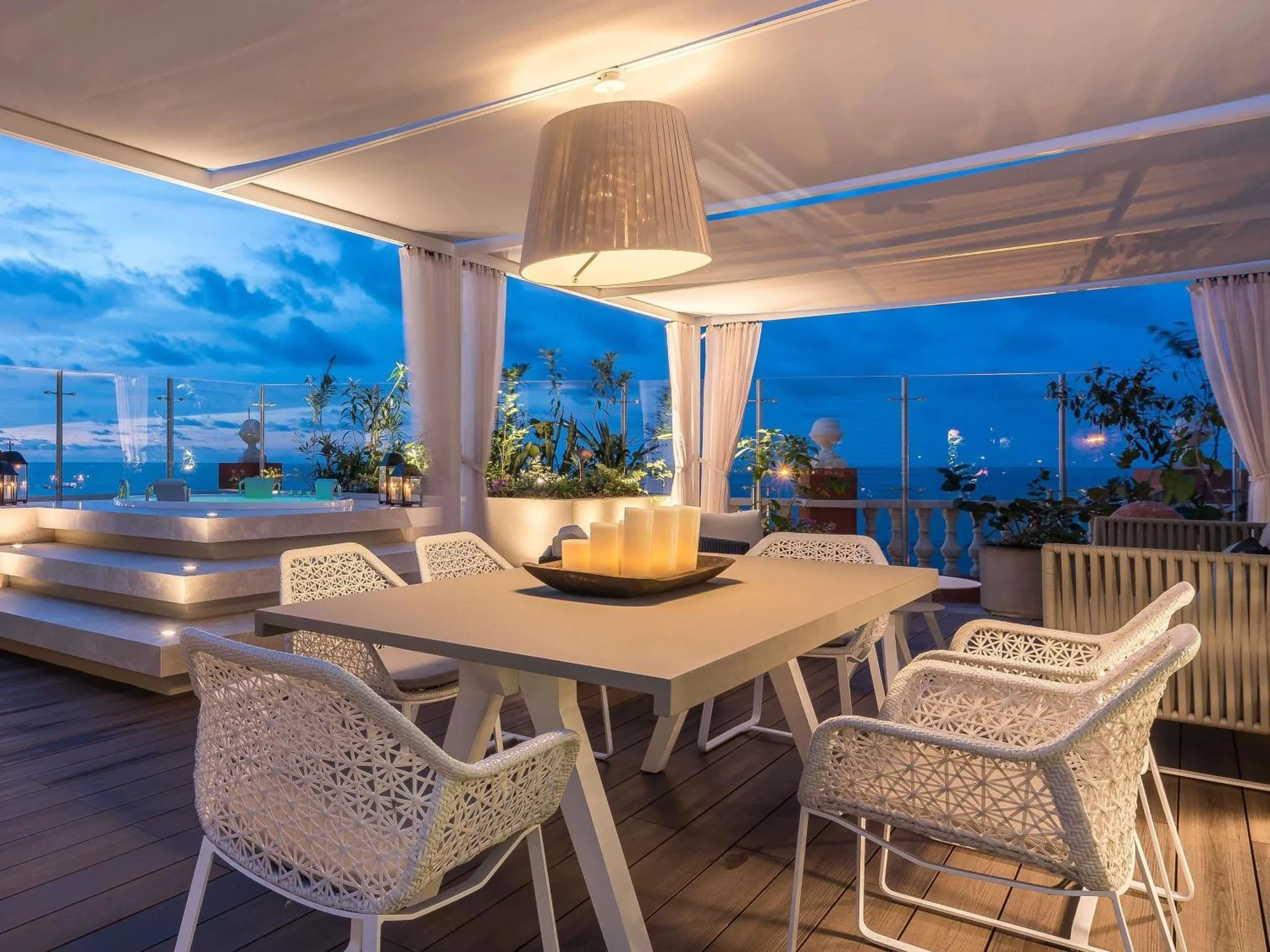 Table à manger sur une terrasse avec vue sur la mer au crépuscule.